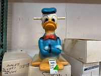 Front view of the Donald Duck blow mold rocking toy showing the blue sailor suit, red bow tie, and yellow feet. Handles extend from the sides of the head.