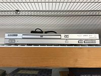 Front view of the silver Magnasonic DVD player showing disc tray, brand logo, and control buttons.