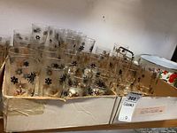 Multiple vintage glassware pieces with decorative black and gold patterns arranged in a box, including tumblers and highball glasses.