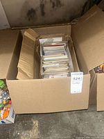 Photo of open cardboard box filled with various greeting cards organized upright inside.