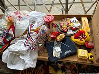 Photo shows a variety of McDonald's collectibles including Ronald McDonald slippers, plates, glasses, badges, and a plush toy, displayed on a wooden surface.