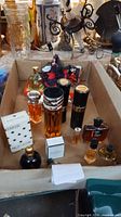Overview of assorted perfume bottles and atomizers in cardboard tray