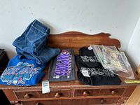 Denim jeans, graphic t-shirts and Star Wars magazines on wooden dresser.