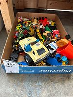Box filled with various colorful toy vehicles including a yellow Fisher Price Mickey Mouse police car and other small toy trucks and cars.
