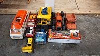 Full lot of assorted vintage toy vehicles including dump trucks, grader, camper, crane, and small plastic vehicles