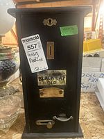 Front view of the Black Cat Dip vending machine showing coin slot, crank handle, dispensing lever, and labels.