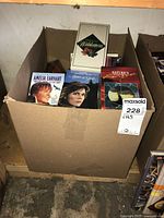 Cardboard box packed with mixed VHS movies including Amelia Earhart, Layers of Gold, and Nature titles