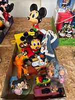 Overview photo showing a variety of vintage Mickey Mouse toys and figures in a box, including plastic and ceramic pieces, small figurines and a toy car.