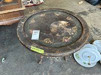 Top view of round wooden side table showing painted floral designs on surface and overall wear.