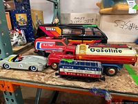 Group photo of the vintage toys showing all items: Tonka trucks, metal race car, gasoline tanker, train car, and Tonka van.