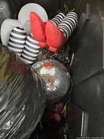 Bin contents showing striped black and white soft decorations, red fabric decorations, and disco ball.