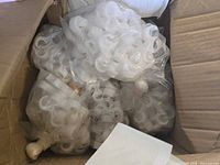 Photo showing multiple white plastic chair connectors bundled separately in clear plastic bags inside a cardboard box.