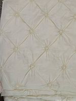 Close-up photo showing the detailed pinched or gathered diamond tufted design of white chair sash fabric.