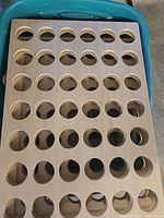 Photo showing large wooden square board with 49 circular holes arranged in 7 rows by 7 columns, natural wood finish.
