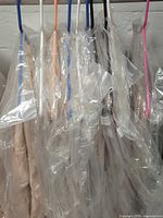 Photo showing 7 hangers holding plastic-wrapped linens suspended on a rack, to display condition and packaging of the linens