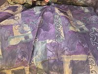 Purple and beige printed tablecloth with abstract swirl and rectangular designs.