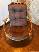 Front view of brown rattan papasan chair with brown polka dot cushion showing circular frame and tufted cushion upholstery.