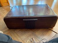 Closed wooden flatware storage chest with ribbed handle and dark polished finish, showing some wear marks on exterior.