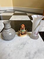 Front view of two vases and the Goebel Hummel figurine on the floor showing colors and shapes