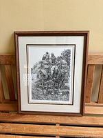 Front image of framed original stone lithograph of 'Harvest Time' by Kathy Hagerman showing detailed black and white artwork with horse-drawn harvest scene, double matting and brown wood frame.