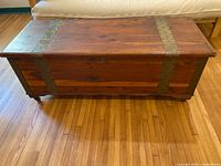 Front view of closed cedar chest showing metal straps across lid and front panel