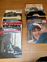 Top view of two stacks of vinyl LP albums arranged on a wooden floor showing album covers and sleeves, highlighting condition and quantity.