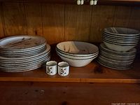 Photo showing the full set including large stack of dinner plates, medium plates, bowls, small plates, and two napkin rings with Midwinter Wild Oats pattern