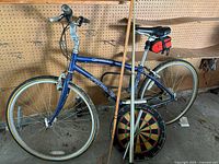 Front view of bike leaning against pegboard wall with hockey stick and dartboard in foreground