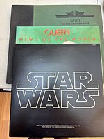 Three vinyl records stacked showing Star Wars record at front, Queen News of the World and Grofé Grand Canyon Suite behind.