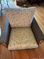 Front view of wicker armchair with seat and back cushions featuring dragonfly and polka dot pattern fabric