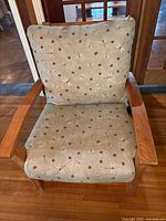 Front view of the armchair showing wood frame and dragonfly printed cushions.