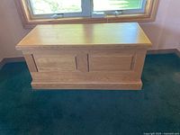Front view of the solid wood storage chest showing the traditional paneled design and natural wood finish.