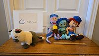Overview of four plush toys including three Disney's Luca characters and a cat plush on a wooden surface