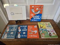 Photo of nine Dr. Seuss books displayed on a wooden table with a white door background. Various titles shown including vintage and newer editions.