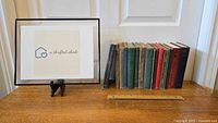 Overview of the 18 antique books lined up on a wooden surface with a display card next to them.