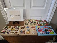 Top-down view showing all five wooden puzzles arranged on a wooden surface. The puzzles include farm animals, farm scenes, a heart-themed cartoon puzzle, and children holding Valentine-themed gifts. The puzzles have bright colors and thick wooden pieces suited for small children.