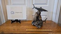 John Perry signed swimming sharks figurine on wooden surface with measuring rulers for size reference.