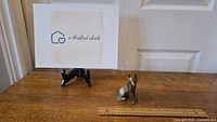 Solid brass German Shepherd figurine placed on a wooden surface beside a ruler for size reference, showing overall shape and condition.