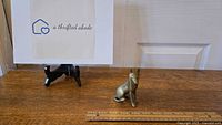 Solid brass German Shepherd figurine on a wooden surface with a ruler for scale.