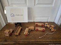 Photo of the full set of vintage wooden trains including various cars and locomotive on a wooden surface.