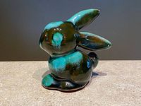 Side view of vintage Blue Mountain Pottery bunny figurine showing green and black drip glaze, glossy finish and tonal variations.
