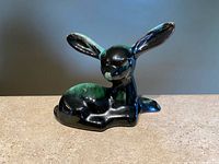 Front side view of blue mountain pottery fawn figurine showing details of green and black drip glaze and long ears.
