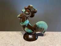 Front angle view of the Blue Mountain Pottery rooster figurine showing the glossy black and green drip glaze with detailed rooster features.