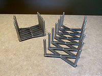 Two stainless steel IKEA VARIERA pot lid organizers side by side on a countertop showing the accordion-style, expandable framework and multiple tall posts.