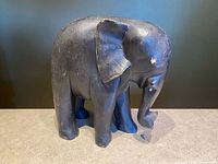Front right side view of the hand-carved solid wood elephant showing dark finish and minor wear.