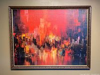 Front view of large vintage abstract cityscape print in carved wood-look and gold-toned frame hung on wall.