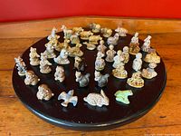 Wide top-down view showing 41 assorted small porcelain Wade Whimsies figurines on a circular black rotating platform featuring various animals and nursery rhyme characters.
