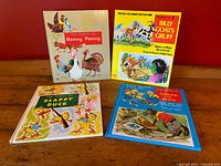 Four vintage children's storybooks displayed with their front covers visible, titles include Henny Penny, Billy Goats Gruff, Slappy Duck, and Three Little Pigs. Covers are colorful with illustrated animals.