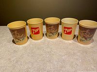 Front view showing the five cups, three displaying Wayne Gretzky in Edmonton Oilers uniform with his signature, and two with the red and white 7UP logo.