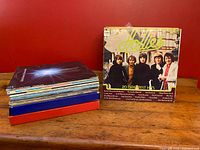 Photo showing the lot of assorted vintage vinyl LP records stacked on a table, highlighting the "Hollies: 20 Greatest Hits" album at the front.